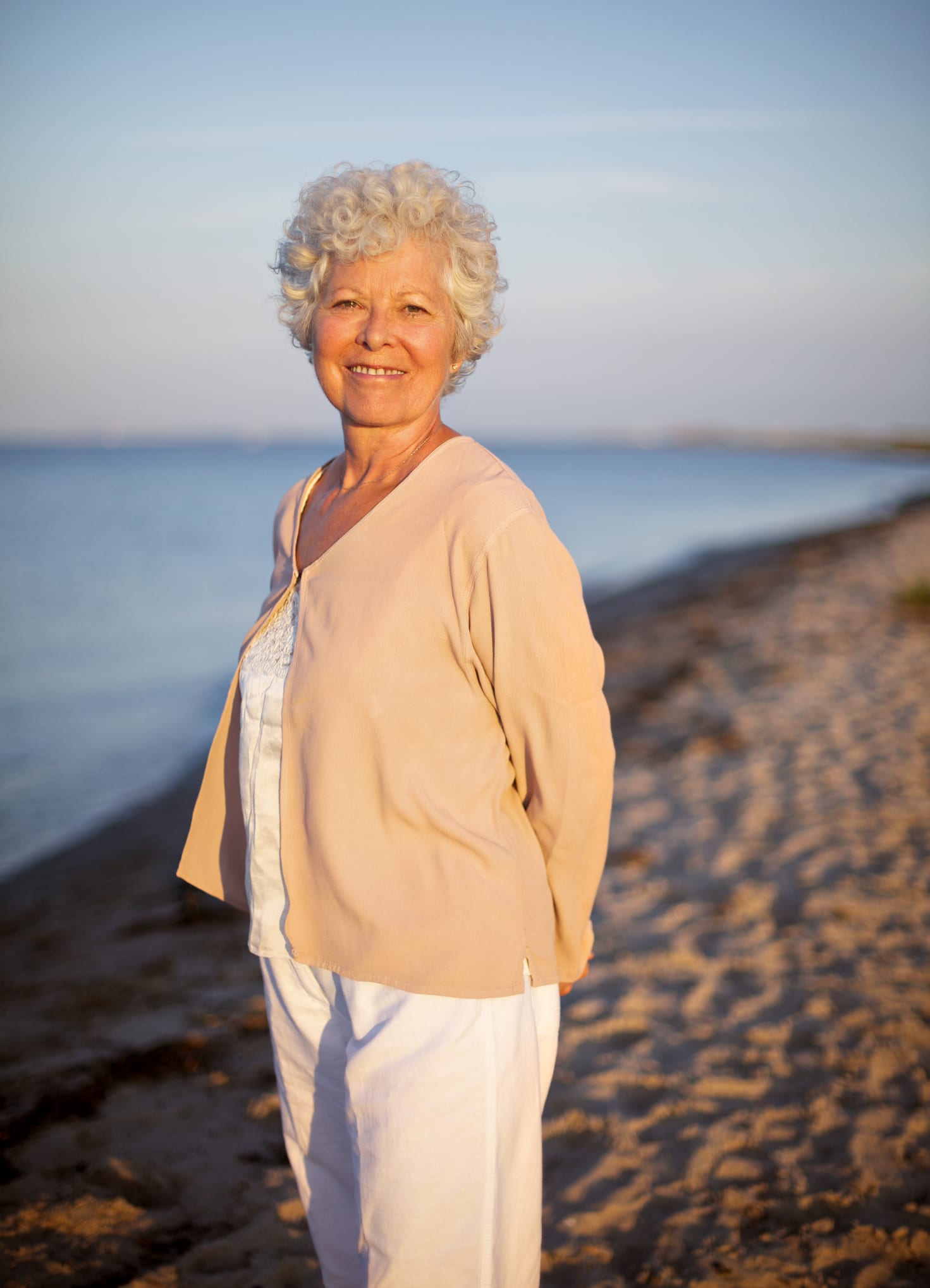 Portrait of elder woman standing alone at the beach. Senior Caucasian lady relaxing outdoors